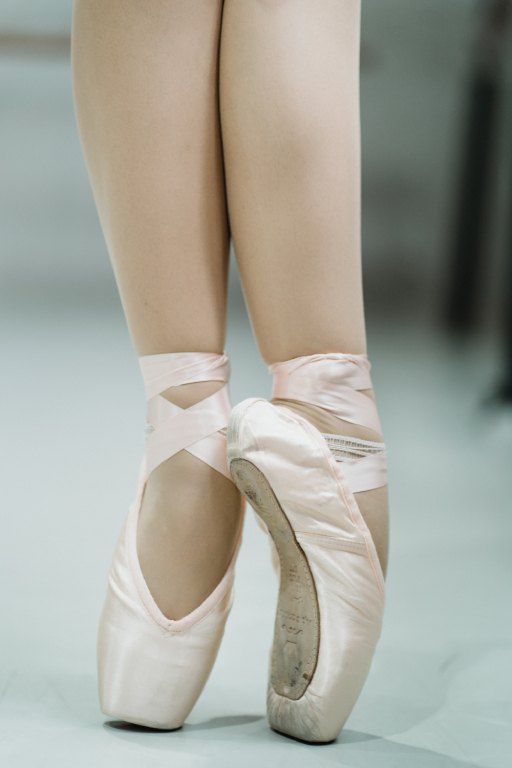 close up of lower calves and toes of cream colored ballet shoes